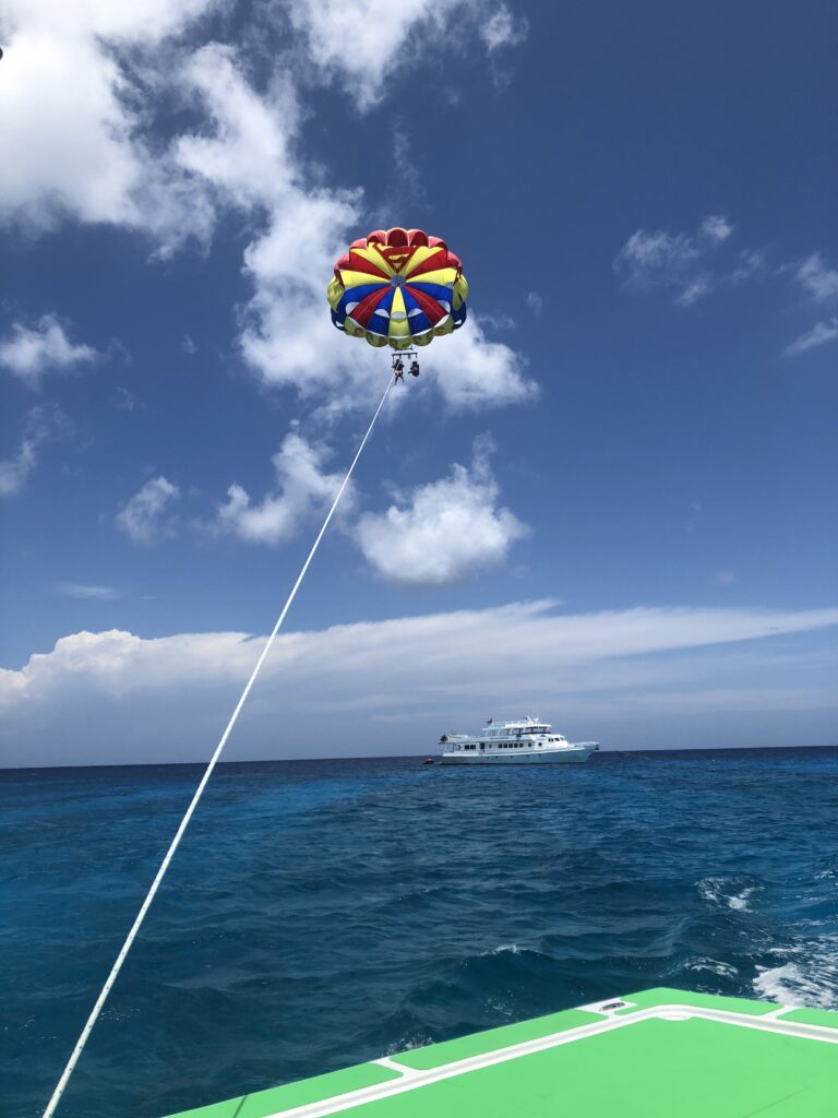 A person flying a colorful kite in the ocean.