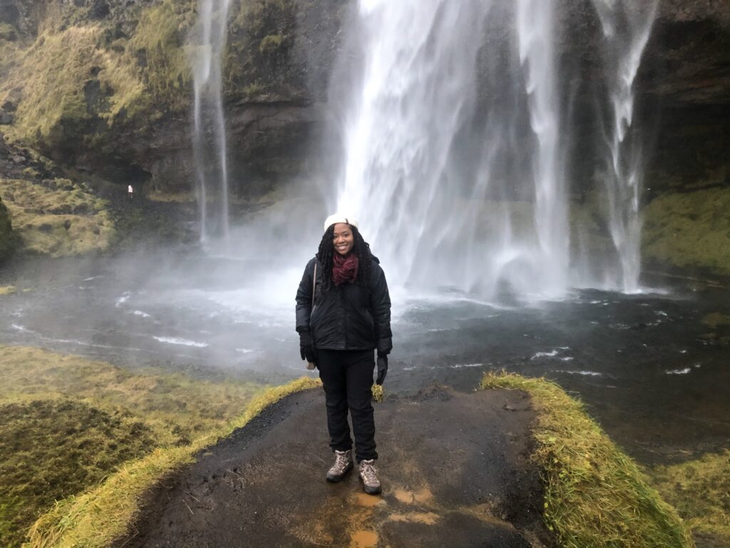 A woman standing in front of a waterfall.