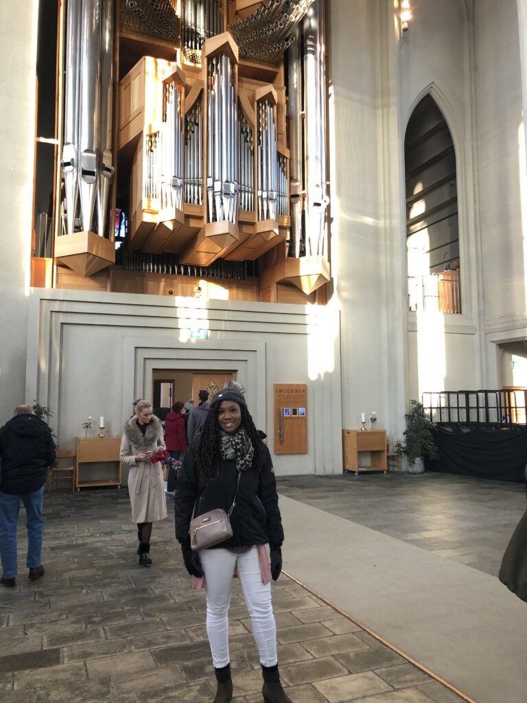 A woman standing in front of an organ.