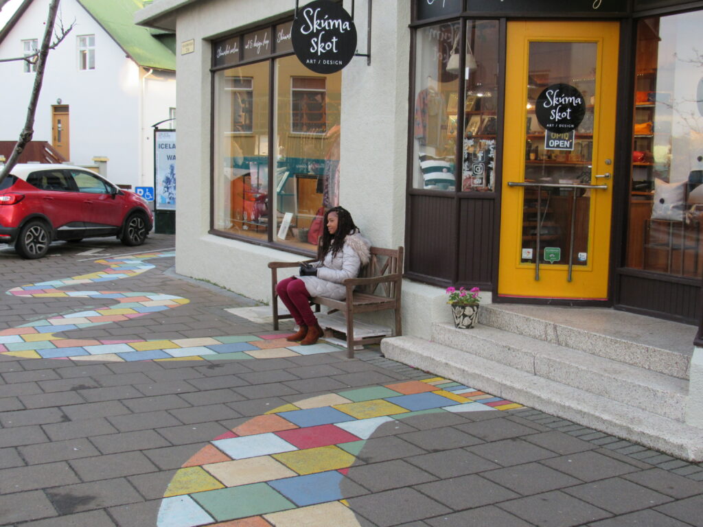 A woman sitting on the bench outside of a store.